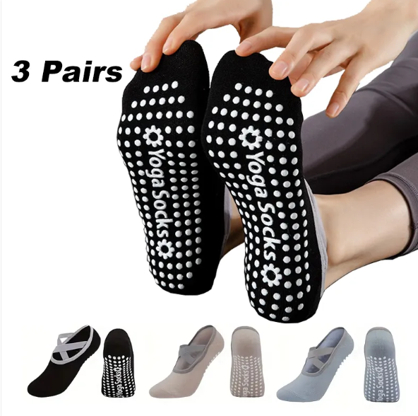 Black yoga socks with white patterns and 'Yoga Socks' branding, held by a person.