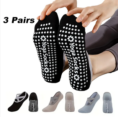 Black yoga socks with white patterns and 'Yoga Socks' branding, held by a person.